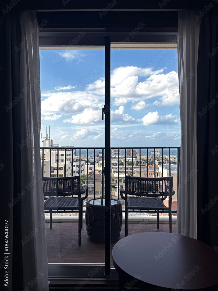 Obraz premium Balcony view of Okinawa Naha and ocean with chairs and table on a sunny day