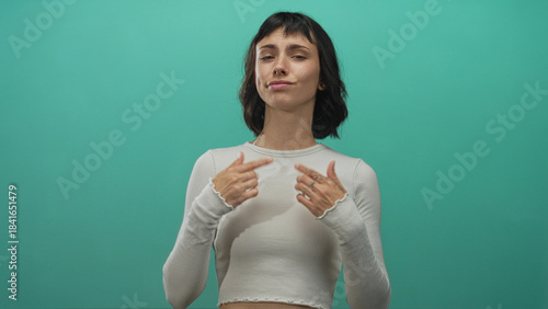 Canvas Print Young hispanic woman with finger pointing to chest and smug look in a teal studio shoot; confidence empowerment self belief