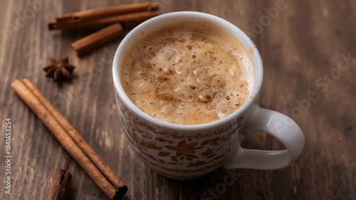 Cozy spiced latte in festive mug with cinnamon on wooden table