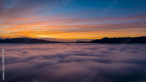Aerial drone over sea of clouds and misty mountains at sunrise