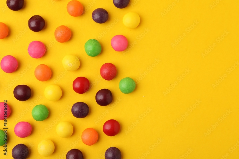 Obraz premium Delicious colorful candies on yellow background, flat lay. Space for text