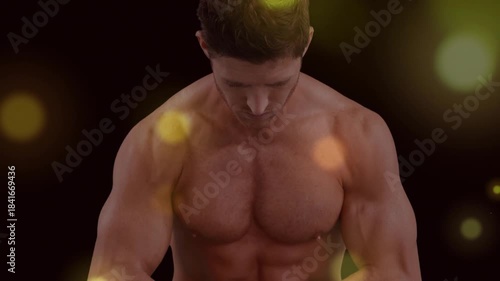 Male fitness model bowing head while camera widening and flares brightening, flexing to show muscle