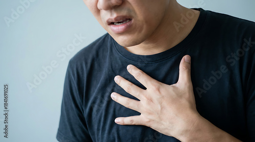 A person placing a flat hand on their upper chest, body slightly tensed, shot cropped at the chin, clean solid-color background.