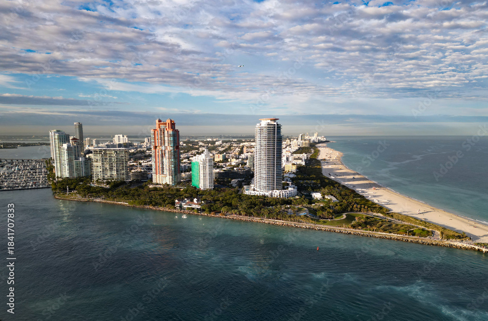 Fototapeta premium Aerial view of Miami city by the coast. Miami skyline with oceanfront skyscrapers. Scenic Miami panorama of Florida famous coastline. Drone shot of Miami above the shore.