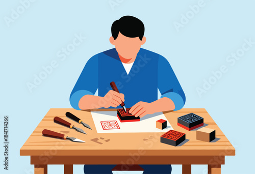Person carving a stamp on paper with tools and blocks on a table