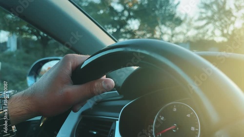 Driver gripping the steering wheel driving with natural morning sunlight highlighting the sunrise scene