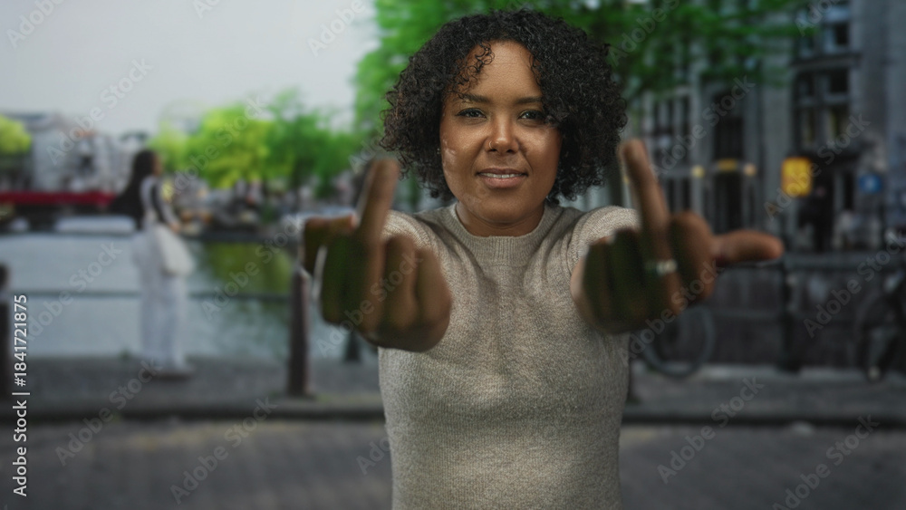 Φωτογραφία Woman flipping both middle fingers with extended arms on a canal city street outdoors; defiance attitude