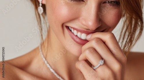 Female model smiling on ivory background wearing diamond ring for jewelry and beauty concept photography