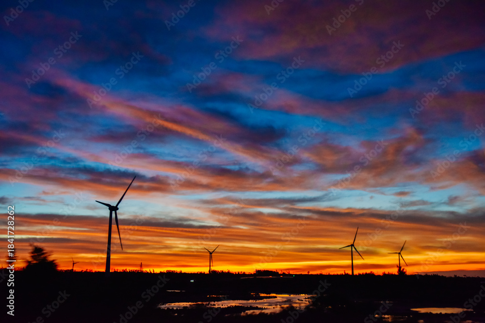 Obraz premium Sunset and Wind Turbine landscape over the Hainan Ring Expressway in Ledong County, Hainan, China, in autumn season