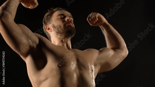 A bodybuilder poses against a black background