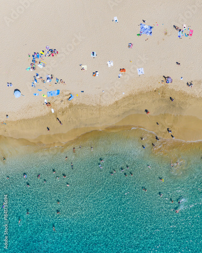 Aerial view of the sun-kissed sands meet the cerulean sea, a vibrant tapestry of beachgoers dotting the coast under the Hawaiian sun, Lahaina, Hawaii, United States.