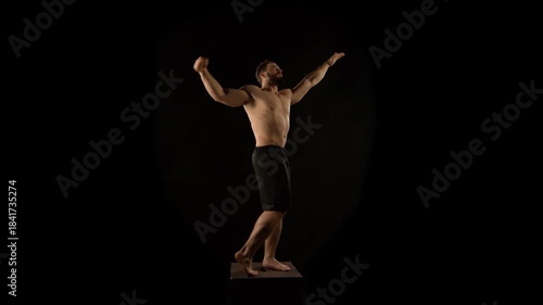 A bodybuilder poses against a black background