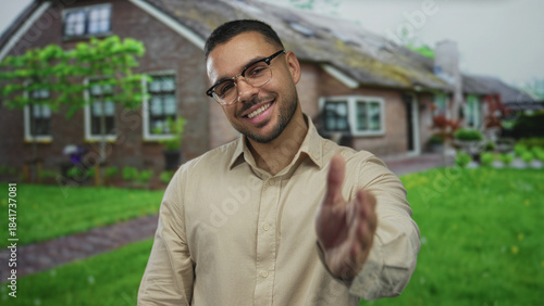 Man extends hand forward for handshake on street with a warm welcoming smile and direct eye contact; friendliness.
