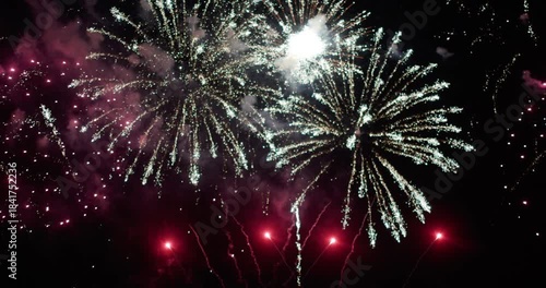A vibrant golden fireworks display illuminating the night sky over a calm water surface, reflecting bursts of golden light, Christmas or New year celebration or countdown