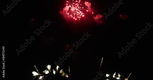 A vibrant golden fireworks display illuminating the night sky over a calm water surface, reflecting bursts of golden light, Christmas or New year celebration or countdown