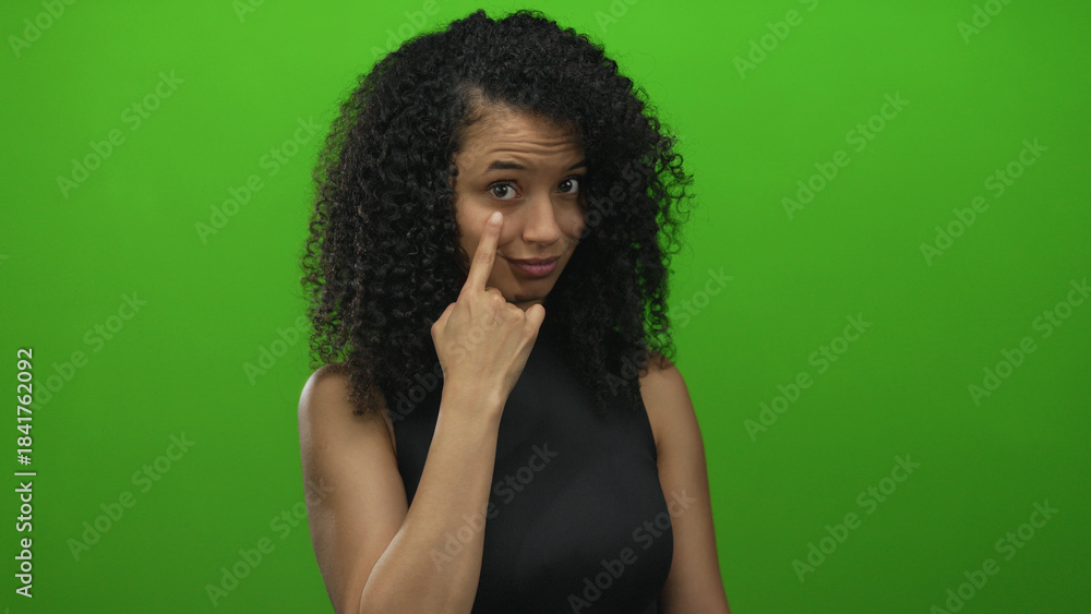 Naklejka premium Woman gestures thoughtfully against a vibrant green background, conveying emotion and expression.