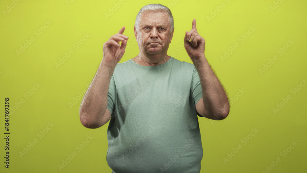 Fototapeta premium Man points finger at camera while holding v with hand over his eye, wearing green shirt in a studio setting; confidence attention.