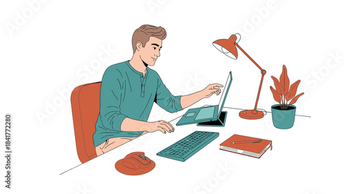 A man working on his laptop at a desk with a lamp, some supplies, and a plant