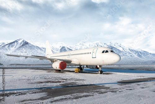 White passenger aircraft on the airport at winter on the background of scenic mountains