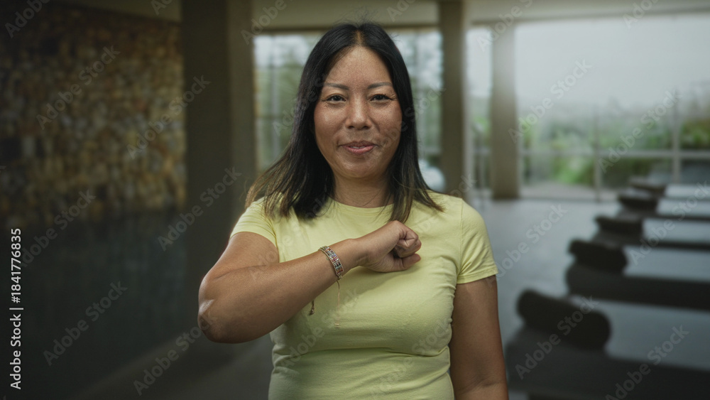Fototapeta premium Woman smiling with eyes closed, arm bent across chest in a spa building near indoor pool; calm contentment.