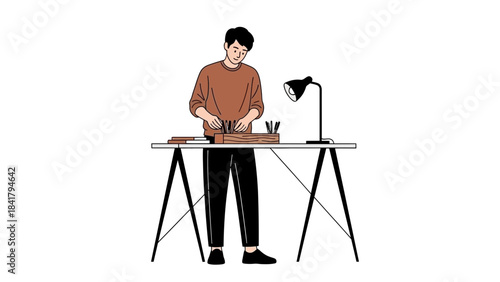 A man is standing at a desk holding pencils and working on creative projects
