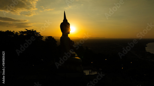 Aerial view at sunset above the Mekong river in Laos revealing Pakse city golden giant buddha
