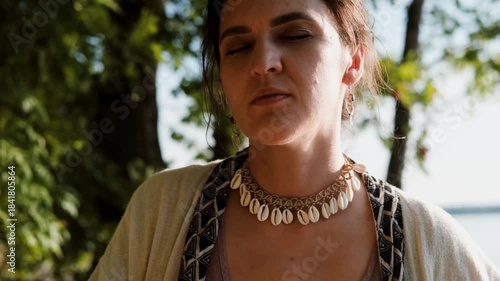 A beautiful brunette dressed in boho style meditates and dances in the forest. A magical ritual takes place against a green forest backdrop.