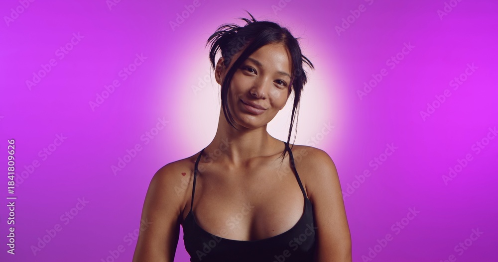 Obraz premium A young Korean model poses in a studio lit by pink neon lights