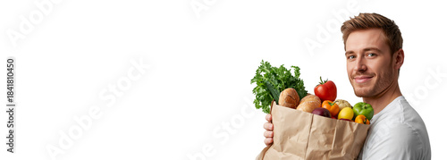 Positive young man with paper shopping bag with vegetables, fruits and bread isolated on transparent background