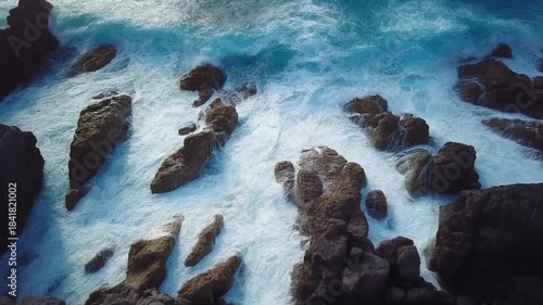 Ocean waves crashing against rugged coastal rocks aerial view