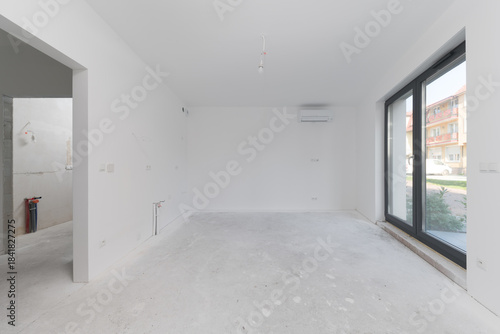 Spacious unfinished room interior with window and doorway