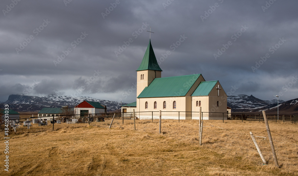 Fototapeta premium Church of faskrudarbakki standing on a hillside overlooking farm buildings in iceland