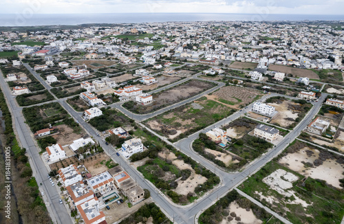 Aerial view of residential area with empty lots and scattered houses in a coastal landscape. Protaras, Cyprus
