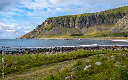 Woman relaxing on rocky coast with mountains in lofoten