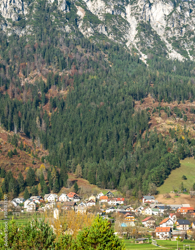 Scenic view of a small village nestled among mountains in autumn with colorful foliage and clear skies