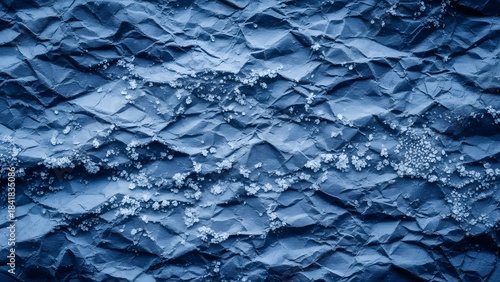 Crumpled blue paper texture with frost-like crystals creating a cold and wintry background