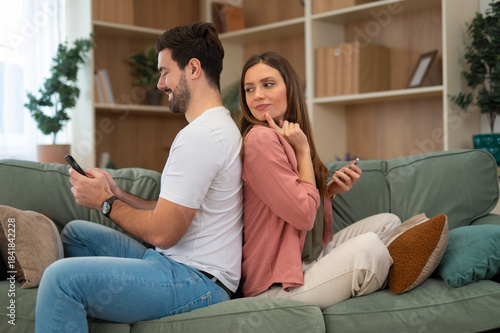 Φωτογραφία Couple sitting back-to-back on sofa showing mistrust