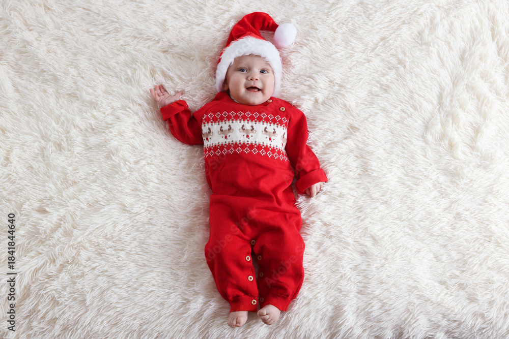 Fototapeta premium Cute little baby in Santa hat on fluffy blanket, top view. Christmas season