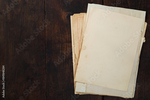 Blank old sheets of paper stacked on wooden table ready for writing or drawing. Old aged paper on wooden table.