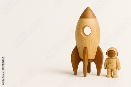 Wooden toy rocket and astronaut on light background. Space for text.