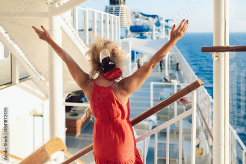Beautiful happy woman on cruise ship deck. Elegant lady in red dress relaxing on vacation. Sea travel and summer holiday. High quality photo