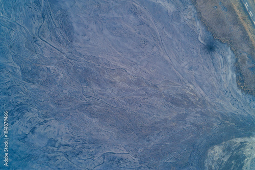 Aerial top down view of blue clay industrial dump surface with soft erosion patterns. Donbas mining waste rock texture and slag pile slope background.