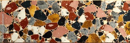 Colorful terrazzo texture background featuring fragmented stone chips in red yellow black and grey embedded in a beige cement base for interior design patterns