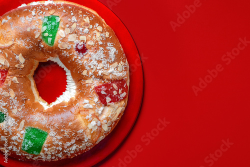 Top view of Roscon de reyes with cream on a red plate and space for text. Kings day concept spanish three kings cake.Typical spanish dessert for Christmas