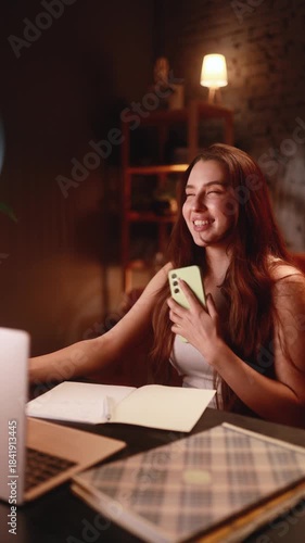 woman joyfully examines her phone, cheerful lady softly acknowledges her positive news notification, woman with joyful expression happily interacts with her device after receiving exciting news