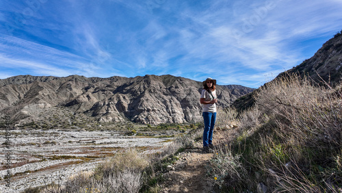 A Woman Geologist on the Trail in the Whitewater Canyon in California evaluating weathering, Erosion, and Runoff along the Whitewater River near Palm Springs to evaluate flood potential