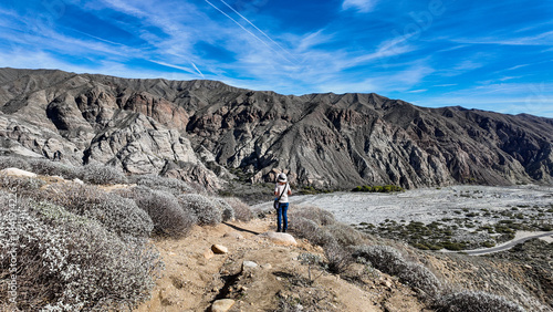 A Woman Naturalist on the Trail at Whitewater River in Palm Springs, California,  Exploring the Terrain and Habitat to teach guests and students about the Environment in a rock stream bed