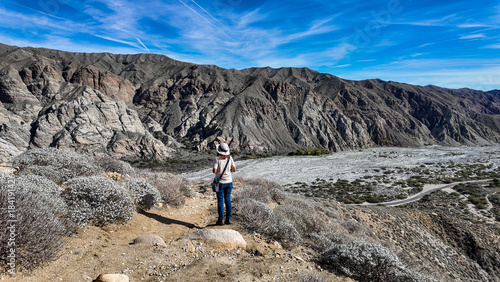 A Woman Naturalist on the Trail at Whitewater River in Palm Springs, California,  Exploring the Terrain and Habitat to teach guests and students about the Environment in a rock stream bed