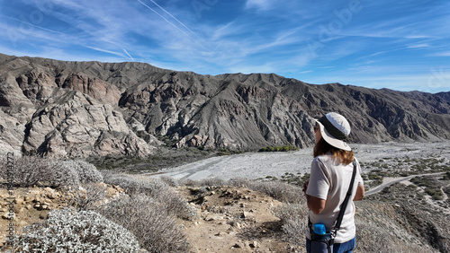 A Woman Naturalist on the Trail at Whitewater River in Palm Springs, California,  Exploring the Terrain and Habitat to teach guests and students about the Environment in a rock stream bed