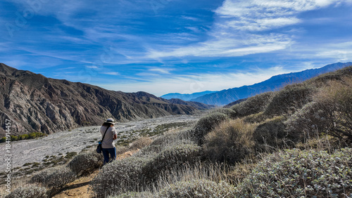 A Woman Naturalist on the Trail at Whitewater River in Palm Springs, California,  Exploring the Terrain and Habitat to teach guests and students about the Environment in a rock stream bed